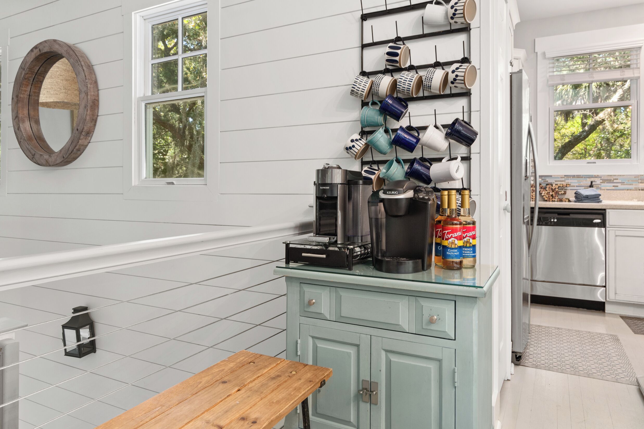A kitchen with a coffee maker, mugs, and a can of Torani syrup on the counter.