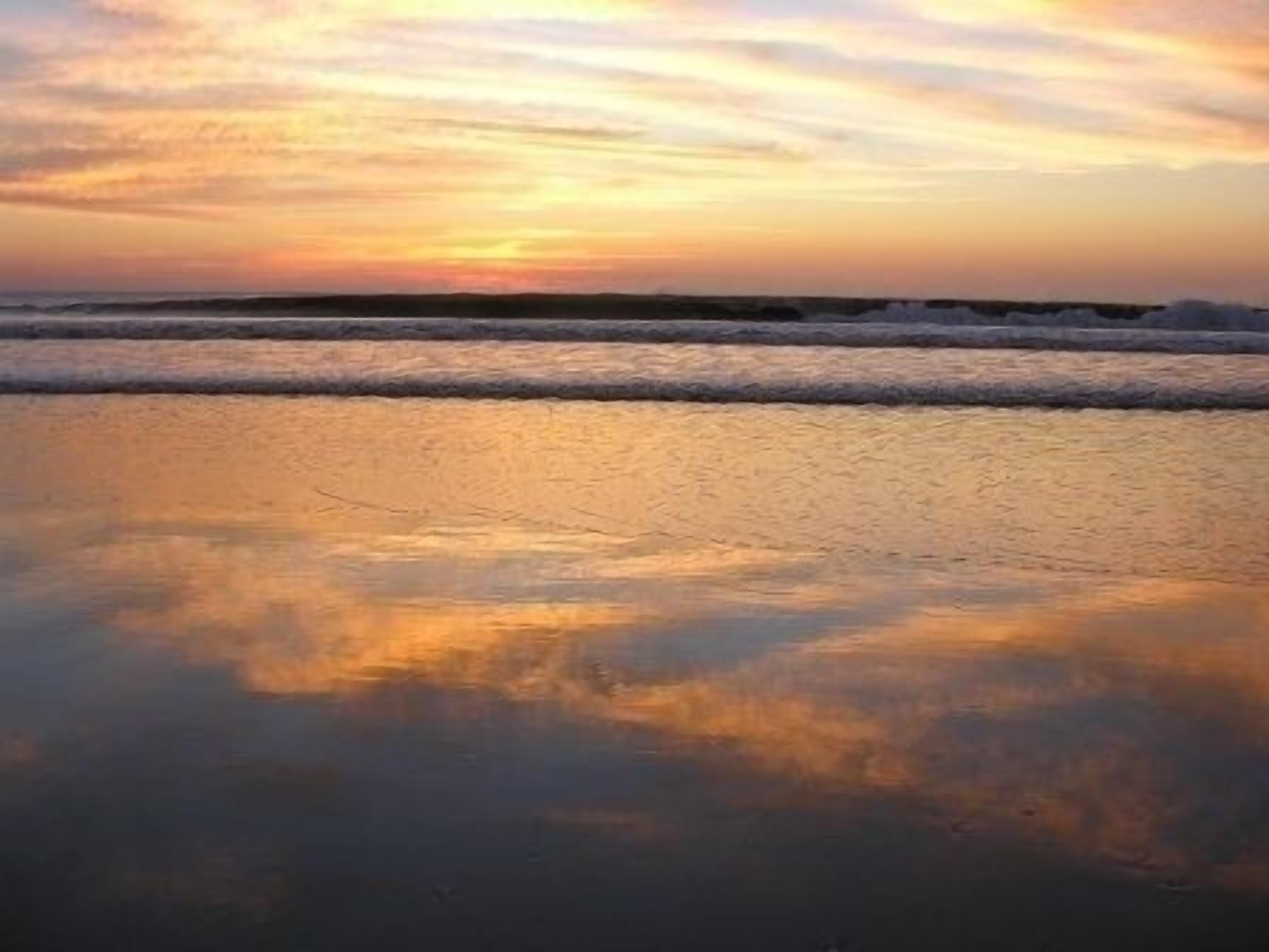 Uma praia com ondas e um pôr do sol.
