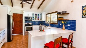 A modern kitchen with white cabinets, a central island, and a ceiling fan. - 4 bed / 4 bath w pool and rooftop patio 50m from Beach in Grande (playa grande)