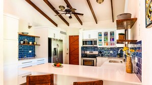 A modern kitchen with a central island, stainless steel appliances, and a ceiling fan. - 4 bed / 4 bath w pool and rooftop patio 50m from Beach in Grande (playa grande)