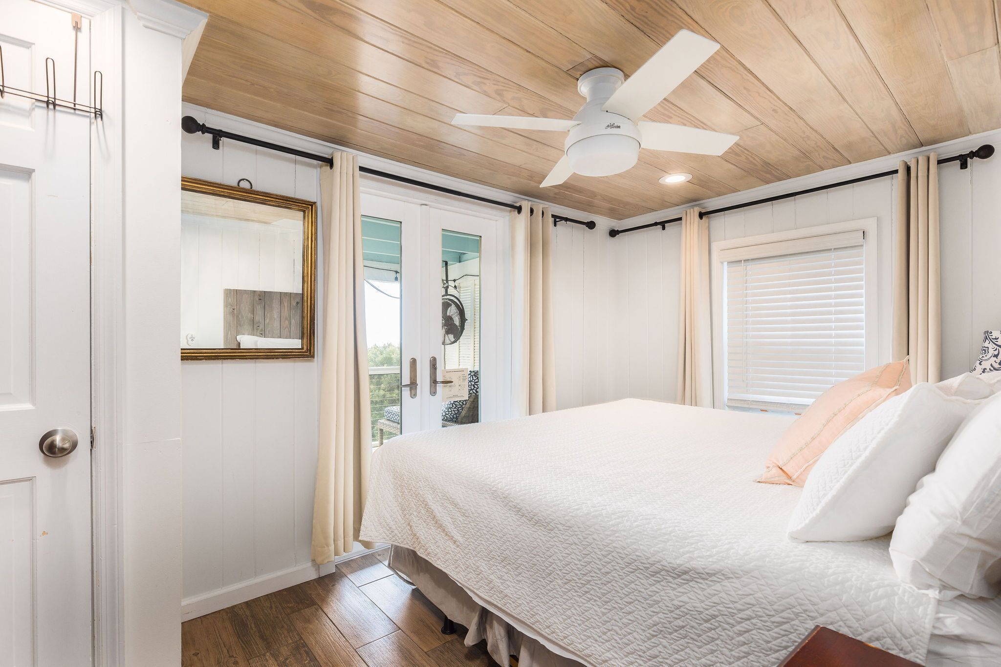 A bedroom with a bed, a ceiling fan, and a sliding glass door leading to a balcony.