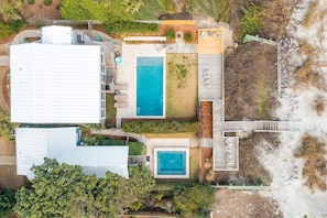An aerial view of a property with a large white building, a swimming pool, and a wooden deck area.