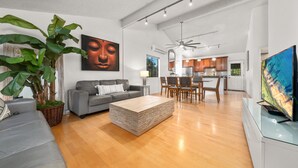 Un salon moderne avec un canapé gris, une table basse en bois et une grande plante.