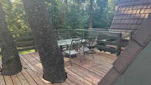 Eine Holzterrasse mit Tisch und Stühlen, umgeben von Bäumen.