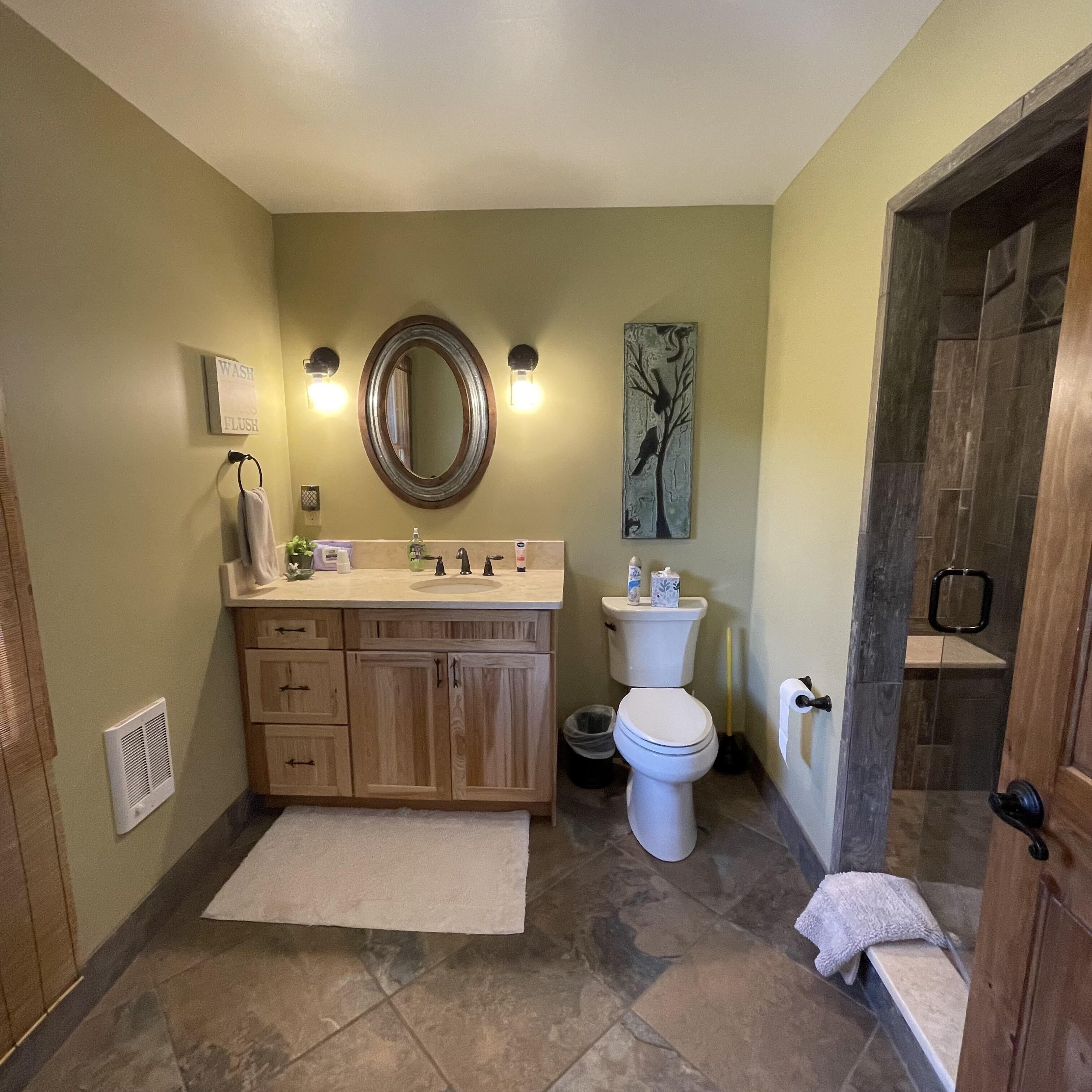 Une salle de bain avec un meuble-lavabo en bois, des toilettes, un lavabo et un espace douche.