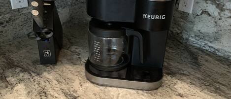 A Keurig coffee maker on a granite countertop with a coffee pod holder and a coffee pot.