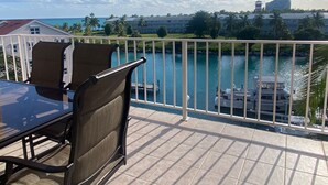 Un balcon donnant sur une étendue d’eau, avec un bateau amarré et un bâtiment en arrière-plan.