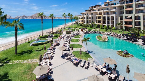 Un complexe hôtelier doté d’une grande piscine, d’un accès à la plage et de plusieurs balcons.