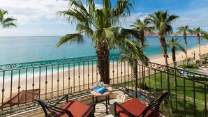 Un balcon avec vue sur une plage, des palmiers et un ciel dégagé.