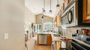 Una cocina moderna con armarios de madera, lavavajillas, estufa y luces colgantes.