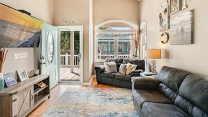 Sala de estar con sofá, televisor, mueble de madera y vistas al exterior.
