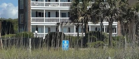 A multi-story hotel with balconies, a beach view, and a sign indicating a keep-off zone.