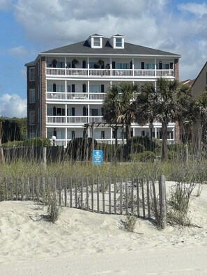 A multi-story hotel with balconies, a beach view, and a sign indicating a keep-off zone. - Pet-Friendly Ocean Front Condo discounted month fall winter months upon approval (Myrtle Beach)