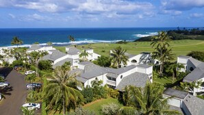 A coastal residential area with houses, a golf course, and the ocean in the background. - Serene Mountain View Condo 11B North Shore Princeville - on Makai Golf Course (Princeville)