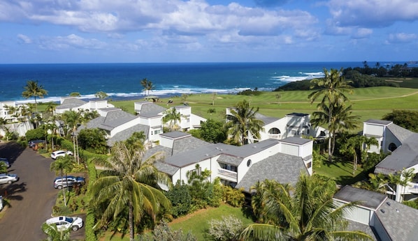 A coastal residential area with houses, a golf course, and the ocean in the background.