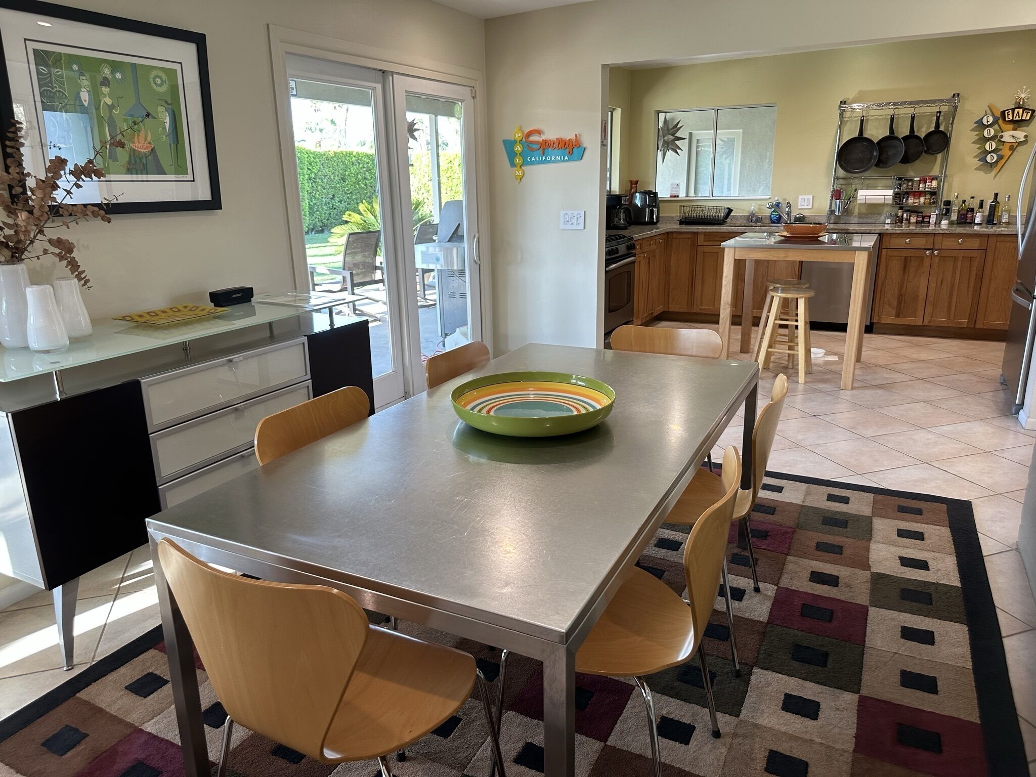 A modern kitchen with wooden cabinets, a dining area with a table and chairs, and a large window.