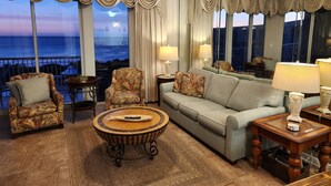 Een woonkamer met een bank, fauteuils, een salontafel en uitzicht op de oceaan.
