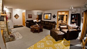 A cozy living room with a fireplace, leather sofas, a coffee table, and a patterned rug.