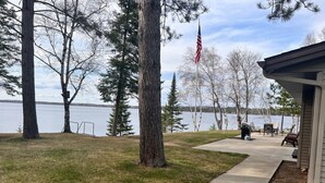 A lakeside property with a concrete pathway leading to a deck area with outdoor furniture.
