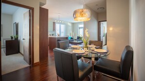 A modern dining area with a glass table, black chairs, and a chandelier. - NEW Aura Newly built and spacious 2 bed, 2 bathrooms (Regina)