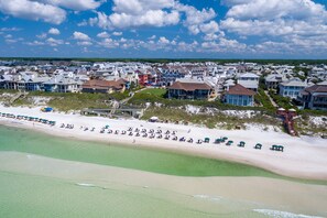Un quartier résidentiel situé sur la côte, avec des propriétés donnant sur la plage, une plage de sable et un ciel dégagé.