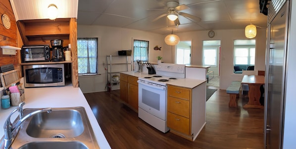 Kitchen features a central island with stovetop and oven, large sink, and refrigerator.