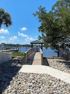 Stroll along the boardwalk to a serene gazebo overlooking the water, surrounded by lush trees.