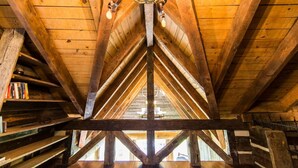A wooden attic room with a sloped ceiling, exposed beams, and a chandelier. - Breathtaking Luxury Log Cabin on TN Horse Farm (Knoxville)