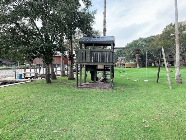 Un parque infantil con una estructura de escalada, columpios y un área cercada.
