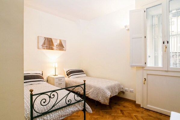 Ein Schlafzimmer mit zwei Betten, einem Nachttisch, einer Lampe und einem Fenster mit Blick.