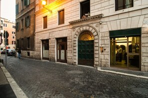 Ein historisches Gebäude mit Kopfsteinpflasterstraße, einer grünen Tür und einem Laden mit großen Schaufenstern.