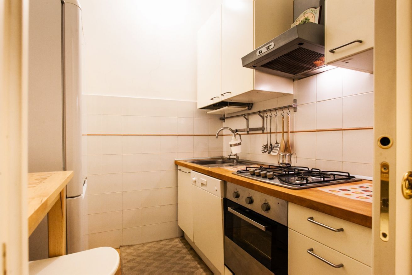 A compact kitchen with a gas stove, oven, and a dish rack.