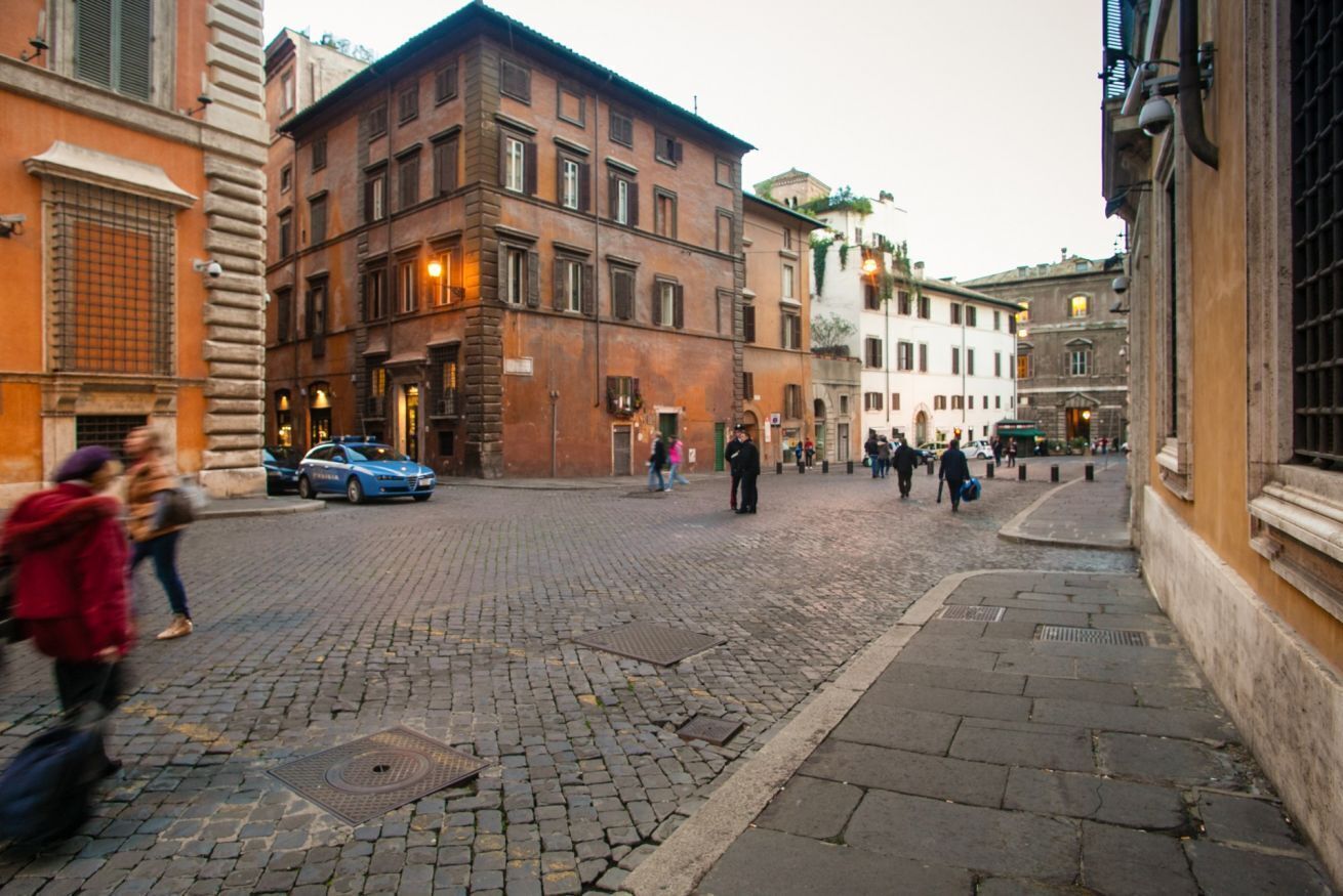 A cobblestone street in a historic European town with traditional buildings and pedestrians.