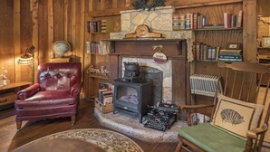 A cozy room with a fireplace, bookshelves, a leather armchair, and a vintage typewriter. - Prairie House. River Cabin. Sleeps 8 (Glen Rose)