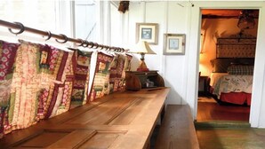A wooden bench with a quilted fabric hanging on a rod, a lamp, and framed pictures on the wall. - Prairie House. River Cabin. Sleeps 8 (Glen Rose)