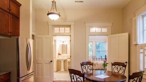A dining area with a round table and four chairs, a refrigerator, and a kitchen area with cabinets and a sink. - 1870's Luxury Guest Cottage, Historic Downtown St. Charles, Mo. (St. Charles)