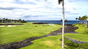 Un campo da golf con vista sull'oceano, palme e cielo sereno.