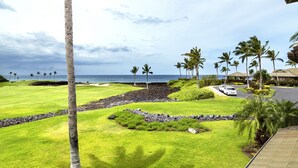 Un campo da golf con vista sull'oceano, palme e un edificio con tetto.