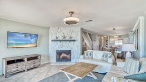A living room with a fireplace, a stone wall, a TV, a wooden coffee table, and a sofa.