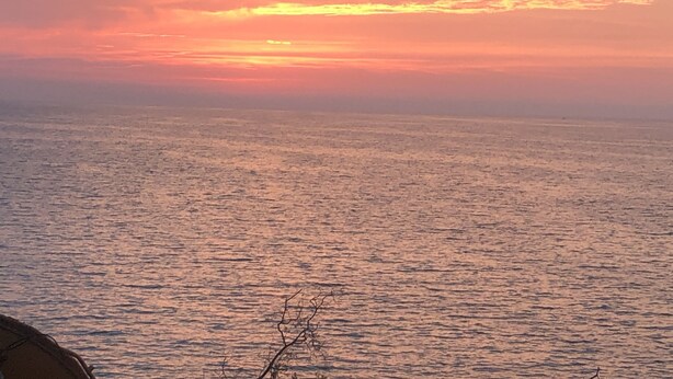Un coucher de soleil sur une mer calme, avec un horizon dégagé.
