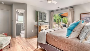 Une chambre à coucher avec un lit, un ventilateur de plafond, une fenêtre avec des rideaux et une vue sur l’extérieur.