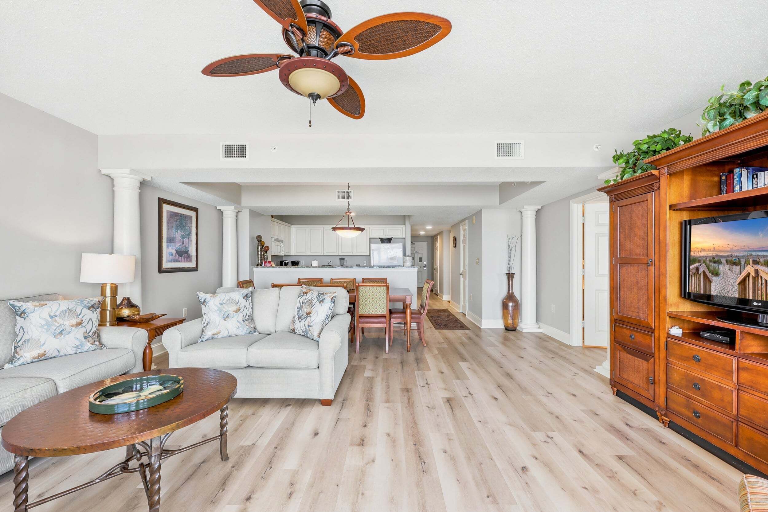 A spacious living area with a ceiling fan, a dining table, and a TV stand.