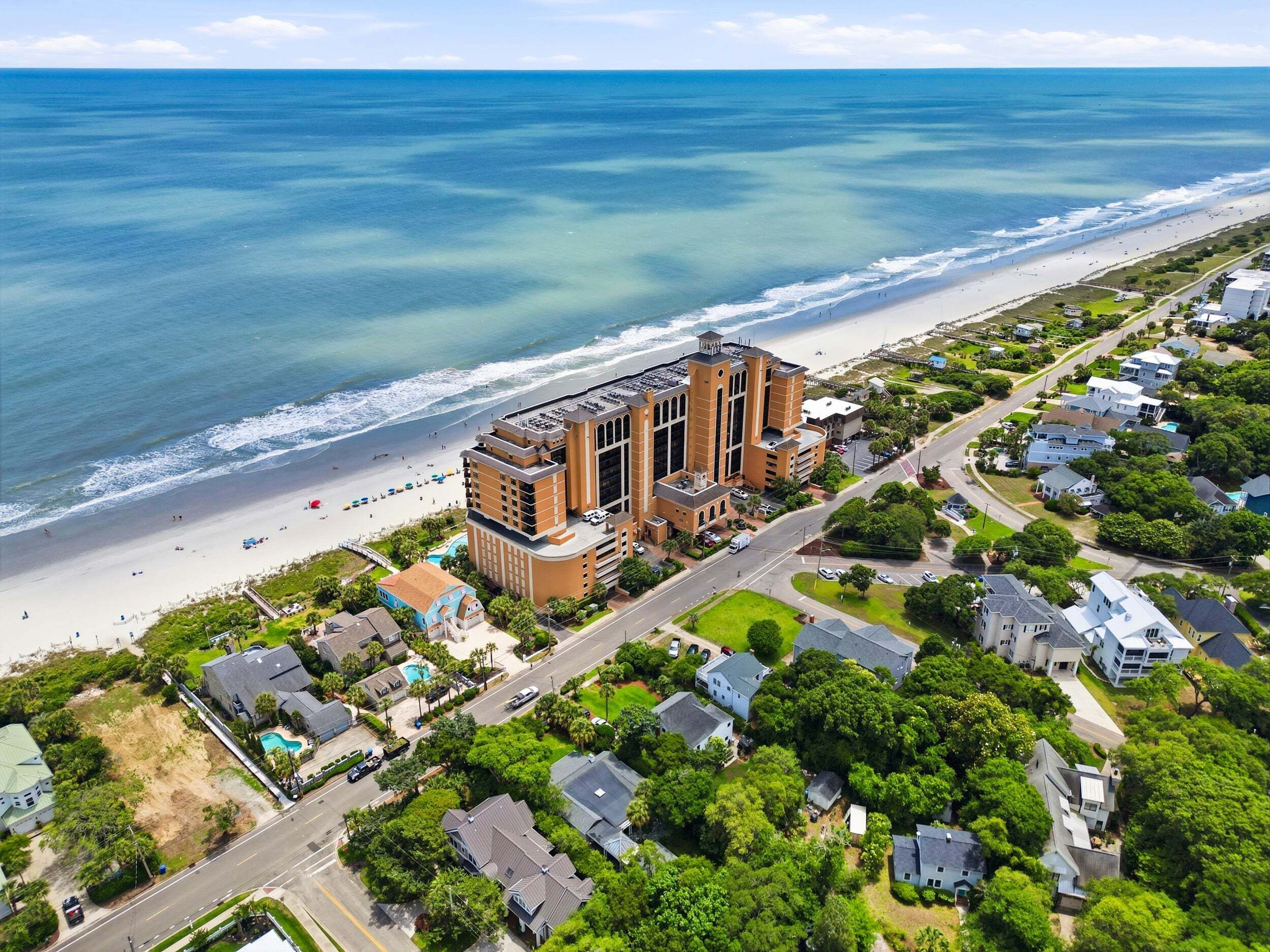 Un hôtel situé sur la côte, doté d’un grand bâtiment, d’un accès direct à la plage et entouré d’un quartier résidentiel.