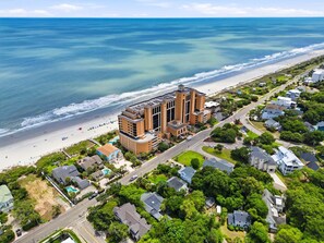 Un hotel costero con una construcción grande, acceso directo a la playa y zonas residenciales aledañas.