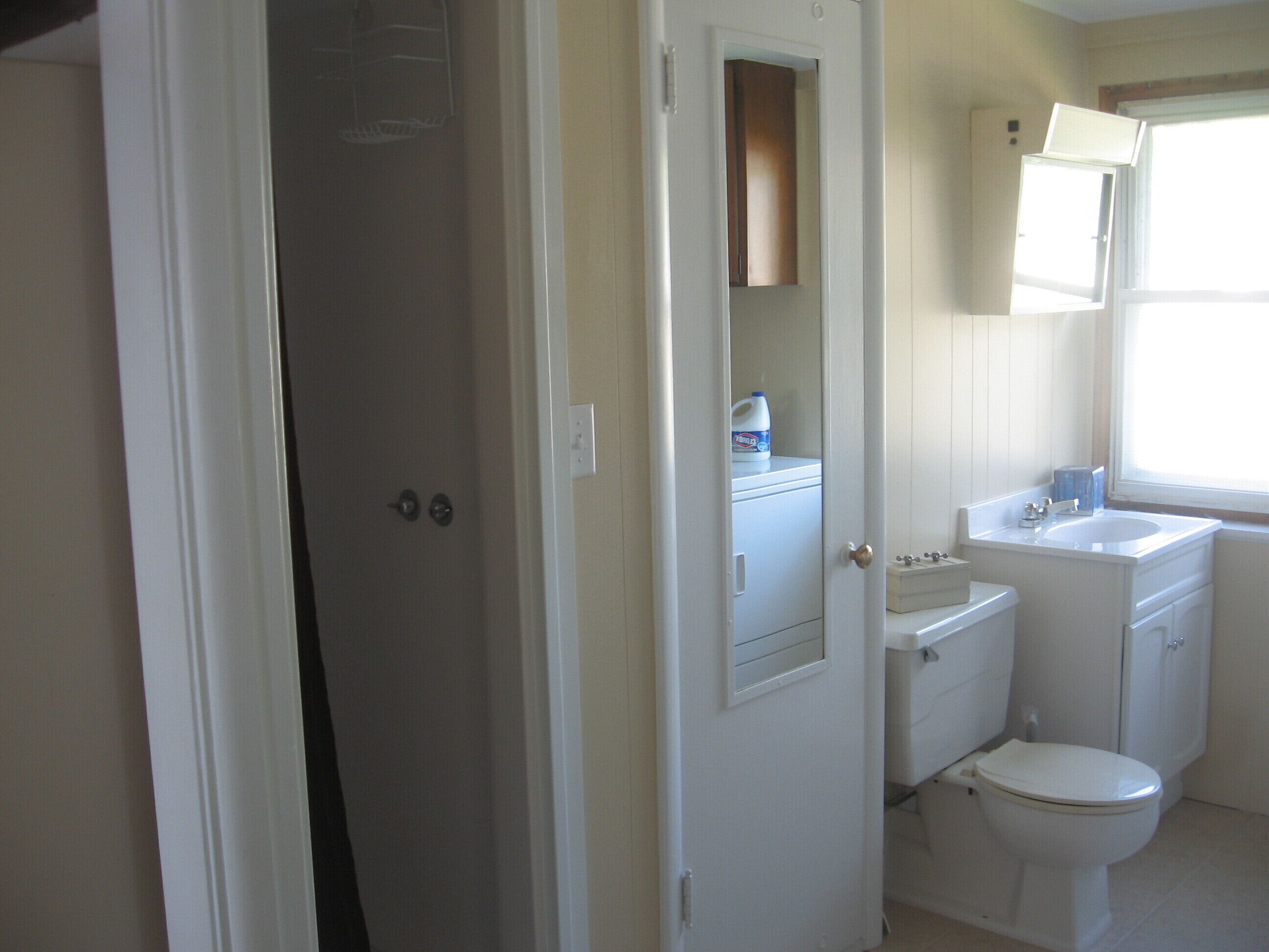 A bathroom with a toilet, sink, and cabinet.