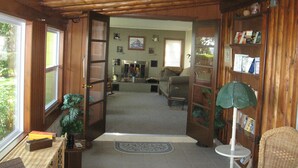 A wooden interior with a living room, a fireplace, and a bookshelf. - Macatawa Lake View Cottage by State Park and Bike Trails (Holland)