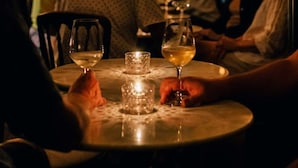 A round table with a candle and two glasses of white wine, surrounded by seated guests in a dimly lit restaurant. -  SPACIOUS HISTORIC DOWNTOWN LOFT!  BEST LOCATION IN THE HEART OF TOWN! (Hermann)