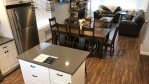 Una cocina moderna con una isla central, muebles blancos y un refrigerador de acero inoxidable.