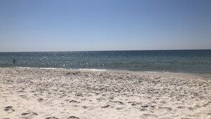 A sandy beach with footprints leading to the water. -     Sun, Sand & Serenity — Your Gulf Getaway Awaits (Gulf Shores)