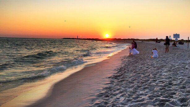A beach at sunset with people walking and sitting on the sand. - Cape May Jackson Street Beach Rental with Ocean Views (Cape May)